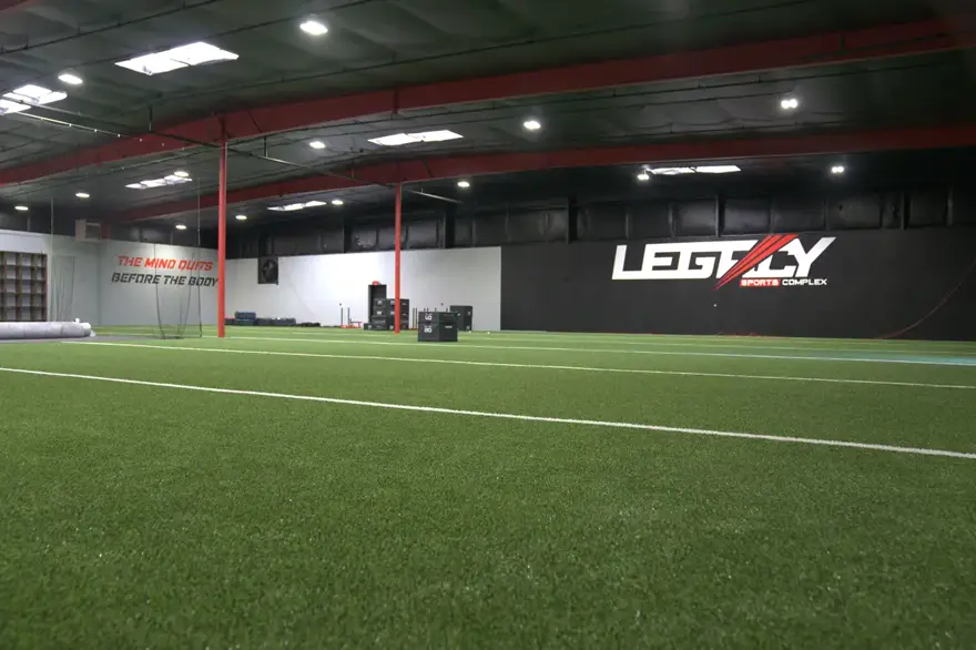 The full indoor turf field with the Legacy mark on the far wall.